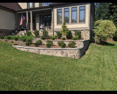 Natural stone retaining wall and landscaping in front of a home